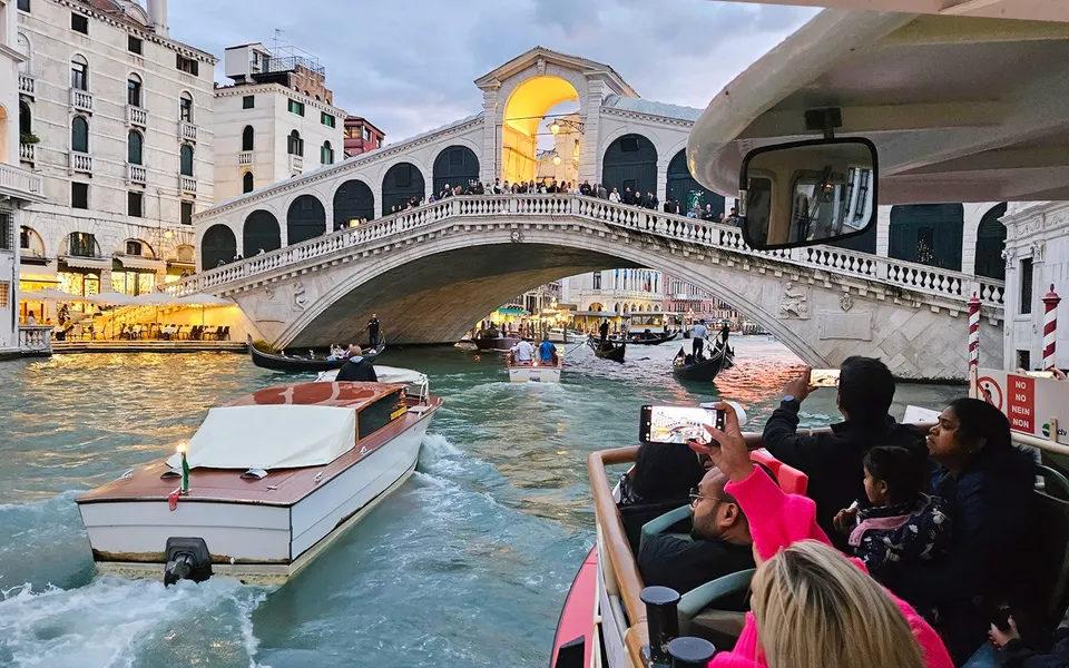 Passengers on a water bus approaching Rialto Bridge