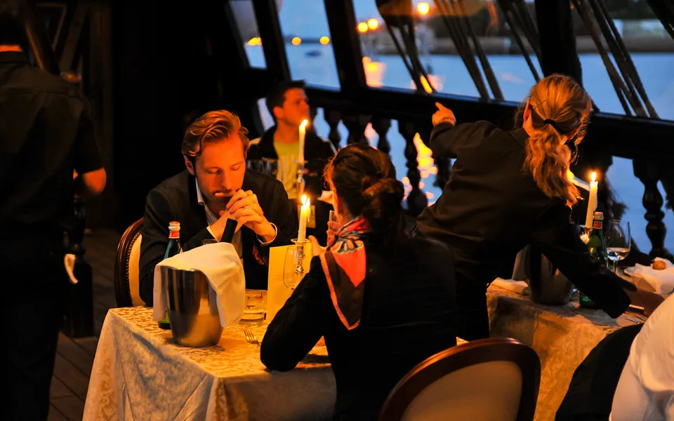 Guests dining at candlelit tables aboard the galleon
