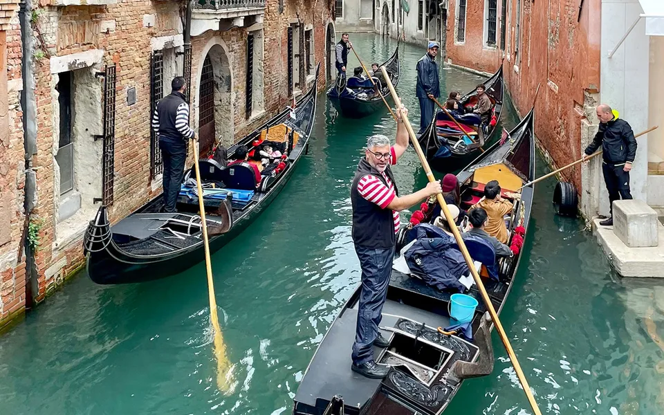 Gondoliers steering through a narrow Venetian canal