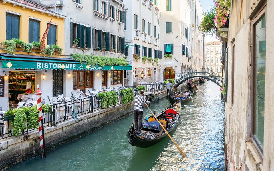 Gondola on a small Venice canal beside waterfront restaurants